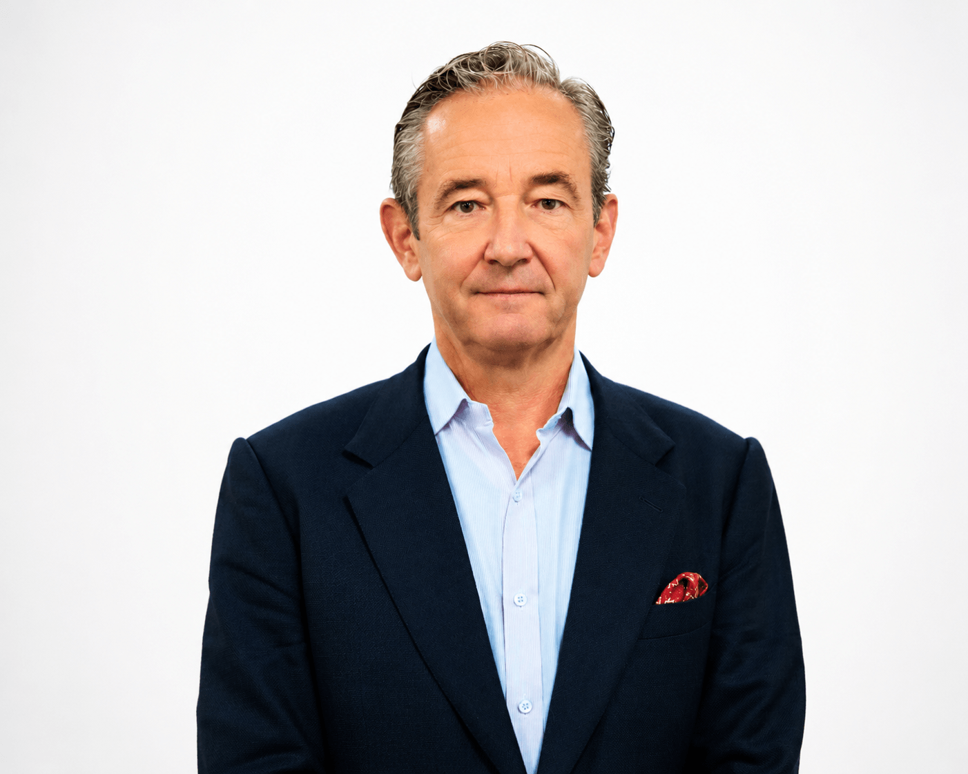 A middle-aged man with short gray hair wearing a navy suit, light blue shirt, and red pocket square stands against a plain white background, looking directly at the camera with a neutral expression.