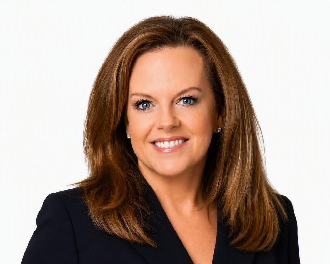 A woman with straight, shoulder-length brown hair smiles at the camera. She is wearing a dark blazer and stud earrings, posing against a plain white background.