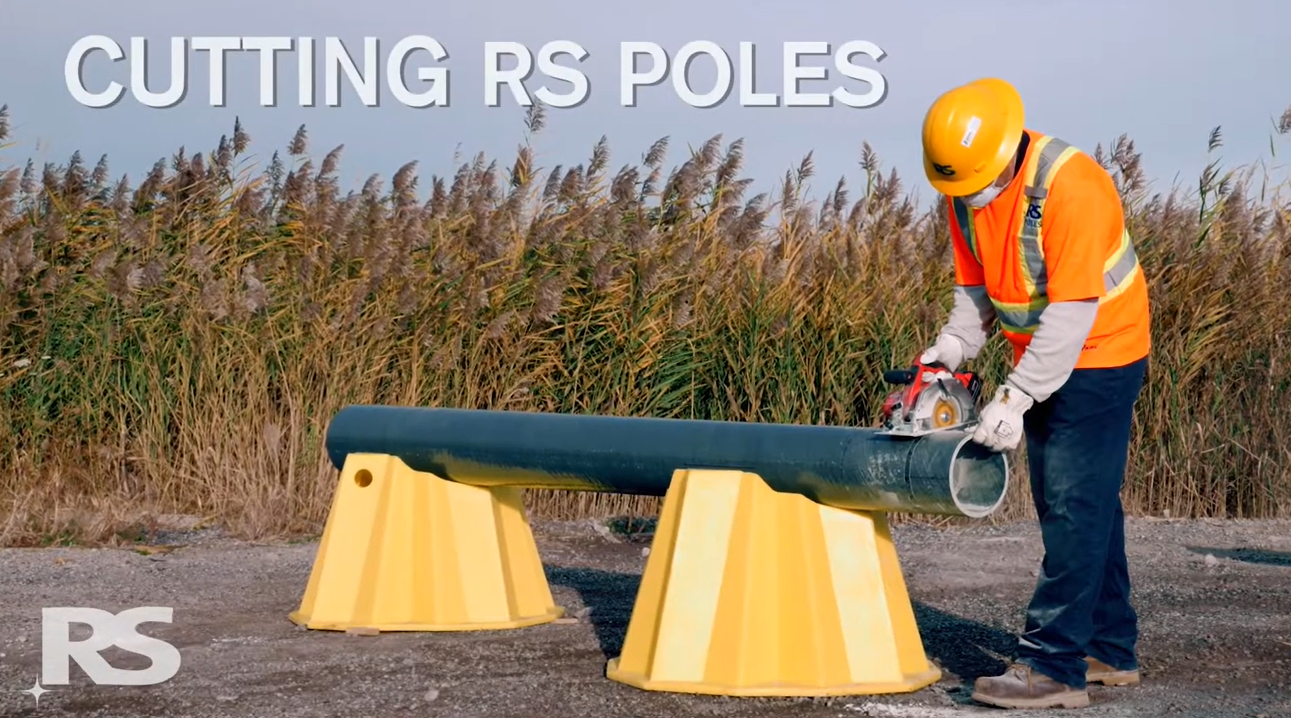 A worker in safety gear uses a power saw to cut a large pole supported by two yellow stands outdoors. The text CUTTING RS POLES appears at the top left.